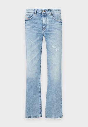 Jeans a campana di colore azzurro chiaro realizzati in denim. Presentano un lavaggio sbiadito, una toppa strappata, cinque tasche e una chiusura con bottone in vita.