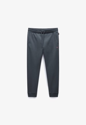 Pantaloni tuta grigio scuro con vita elastica, cordoncino, tasche laterali e gambe affusolate. Il tessuto ha una superficie liscia e un piccolo dettaglio del logo.