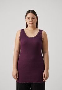 Canotta viola a coste con pizzo sullo scollo e sulle braccia. Tessuto texturizzato con orlo a onda. Design aderente, taglio a lunghezza intermedia.