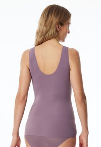 Débardeur violet avec un dos échancré et de larges bretelles, fabriqué en tissu lisse et extensible. Présente un design ajusté qui épouse le corps.