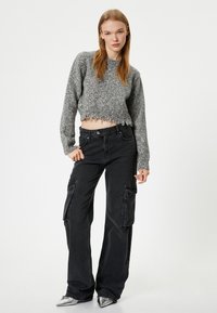 Geknipt grijs sweatshirt met een textuur breiwerk en een rafelige zoom, gecombineerd met hoge zwarte cargobroek met zijzakken en een relaxte pasvorm.