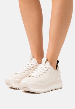 Sneakers bianchi in tela con suola spessa, caratterizzati da un motivo testurizzato, punta arrotondata e inserto sul tallone in nero a contrasto. Design con lacci, stile low-top.