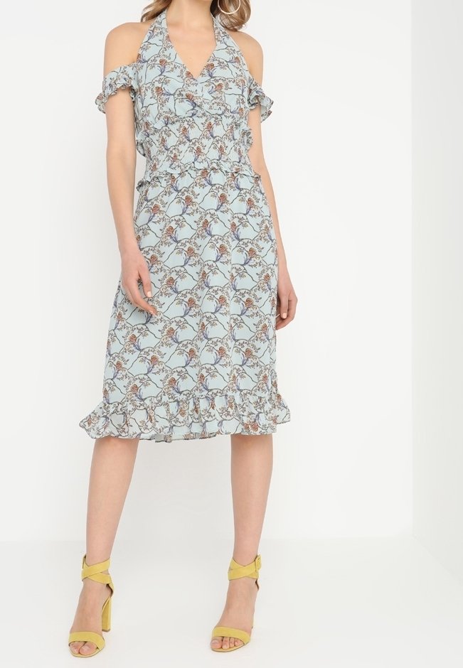 Ljusblå blommig klänning med cold-shoulder design, volangärmar, figurnära midja och fransad nederkant. Matchas med gula sandaler.