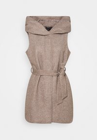 Ärmlös kappa i ljusbrunt tyg, försedd med en stor huva, bälte i midjan och en strukturerad yta med ett subtilt mönster.