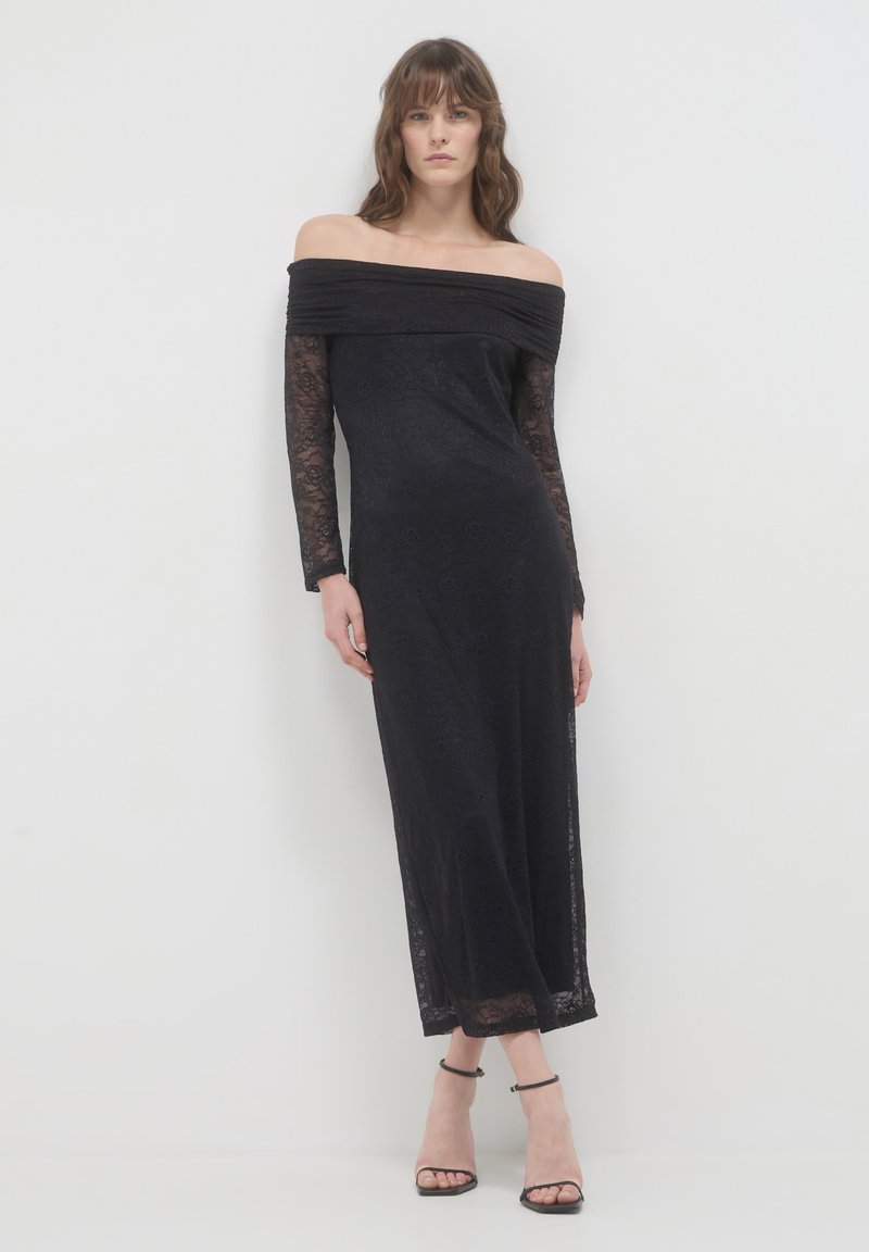 Robe noire à épaules dénudées avec de longues manches en dentelle, un corps ajusté et une jupe fluide. Présente un motif floral texturé sur l'ensemble.