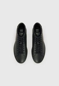 Zapatillas deportivas de cuero negro con superficie texturizada, puntera redonda, cierre con cordones y plantillas ortholite. Presentan un sutil logotipo en la lengüeta.