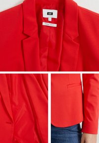 Red blazer with a notched collar, smooth texture, and subtle sheen. Features a single chest pocket and a tailored fit.