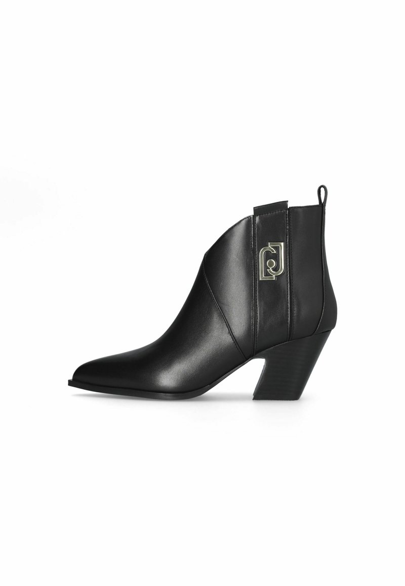Schwarze Leder-Stiefelette mit spitz zulaufender Zehenpartie und einem Blockabsatz in mittlerer Höhe. Mit einem dekorativen metallischen Logo-Akzent und einer Zuglasche.