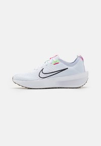 Bílé sportovní boty s texturovaným síťovaným svrškem, černým logem swoosh a barevnými akcenty v růžové a zelené na očkách a patě.