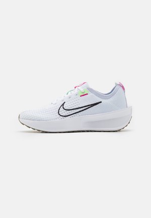 Baskets blanches avec un upper en mesh texturé, un logo swoosh noir et des accents colorés en rose et vert sur les œillets et la languette arrière.