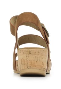 Sandale compensée en daim brun avec plusieurs brides, semelle en liège et un bouton d'accent rond sur le côté. Texture lisse et design ouvert à l'arrière.