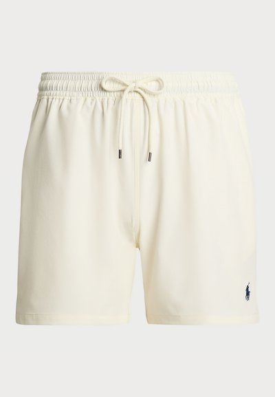 Cream-colored swim shorts with an elastic waistband, drawstring closure, and a small navy logo on the lower left side. Smooth fabric texture.