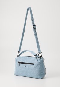 Borsa in denim azzurro chiaro con tasca con zip, manico superiore e tracolla regolabile. Presenta accessori neri e tessuto texturizzato.