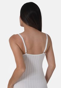 White fitted bodysuit with thin straps, vertical ribbed texture, and adjustable hardware at the shoulders. Back view showcased.