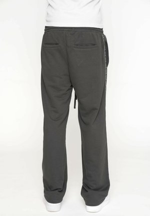 Pantaloni della tuta grigio scuro con vestibilità comoda, vita elastica, cordino e due tasche posteriori. Realizzati in un morbido tessuto texturizzato.