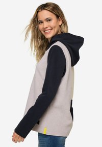 Felpa con cappuccio di colore grigio chiaro, maniche e cappuccio blu navy, con un accento giallo all'orlo e una texture morbida.