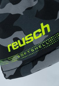 Schwarz- und graufarbenes Tarnmuster auf einem Softshell-Stoff mit leuchtendem grünen "reusch"-Logo und dem Text "SOFTSHELL" entlang des Randes. Glatte Textur.