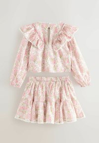 Dievčenský dvojdielny outfit s dlhými rukávmi, volánovým golierom a elastickou sukňou v páse, s ružovo-zeleným kvetinovým vzorom na bielom materiáli.