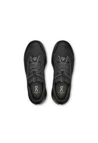 Chaussures de trail noires avec une tige en maille texturée, un embout renforcé, des lacets plats et un logo signature sur la languette et la semelle.