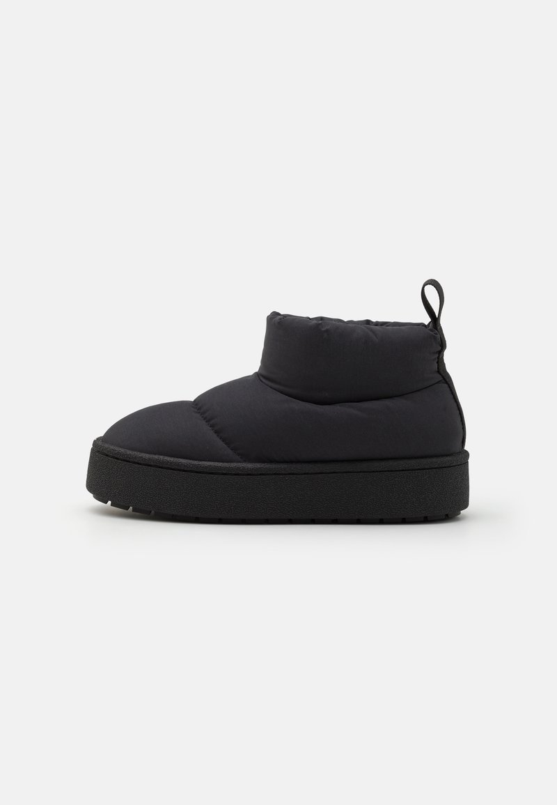 Mustad ja pehmendatud ankle boots ümmarguse varbaga, pehme tekstuuriga ja paksu musta tallaga. Tagaküljel on mugavamaks selga tõmbamiseks tõmbeaas.