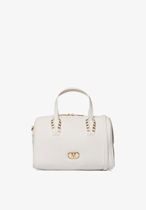 Sac à main en cuir blanc avec double anses, clous dorés, fermeture éclair, et une plaque logo dorée sur le devant.