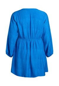 Zila austā tērpa ar apaļu kakla izgriezumu, garām piedurknēm un sapulcinātu vidukli. Raksturota ar teksturētu rakstu un vaļēju piegriezumu.