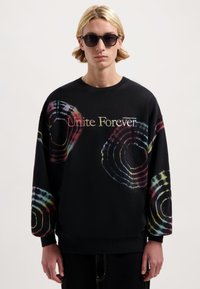 Zwarte katoenen sweatshirt met multicolor spiraal tie-dye patronen. Heeft een ronde halslijn en bedrukte tekst "Unite Forever".