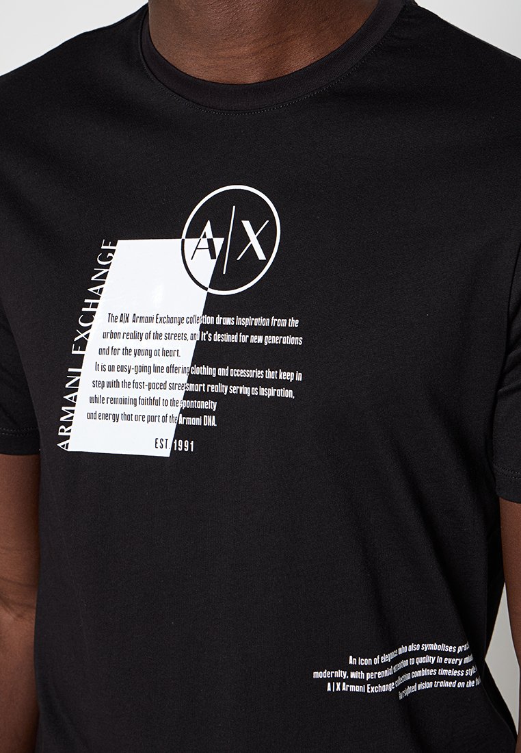 Czarna bawełniana koszulka z okrągłym dekoltem, z białym graficznym napisem i logo "A/X" w okrągłym wzorze. Napis zawiera nazwę marki oraz rok założenia.