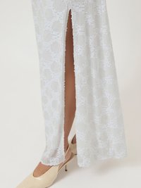 Λευκό φόρεμα με λεπτομέρειες από πούλιες, featuring άνοιγμα στο πλάι. Λείο ύφασμα με γεωμετρικά σχέδια υφής. Συνοδευόμενο από γυμνά τακούνια.