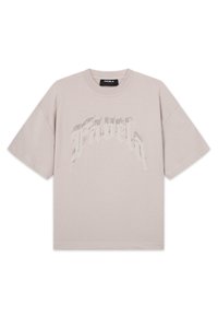 T-shirt beige à manches courtes avec un col rond et un subtil motif de texte stylisé sur la poitrine indiquant « FAVELA ».