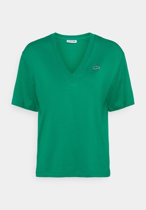 T-shirt Lacoste vert à manches courtes et col en V avec petit logo crocodile sur la poitrine gauche, présenté sur fond blanc.