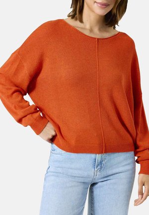Un pull en tricot orange avec une coupe décontractée, un grand col et des manches longues. L'ourlet est côtelé, ce qui lui donne une finition texturée. Associé avec un jean clair.