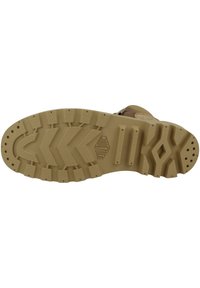 Semelle de botte marron avec un motif de profondeur robuste, présentant des bords dentelés et une surface texturée pour une meilleure adhérence. Logo estampé près du talon.