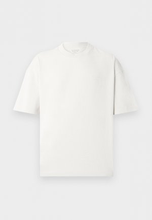 Weißes, übergroßes T-Shirt mit kurzen Ärmeln, Rundhalsausschnitt und dezentem, geprägtem Logo auf der linken Brust.