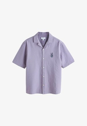Lawendowa koszula na krótkie rękawy z guzikami, wykonana z teksturowanej tkaniny, z małymi haftowanymi niebieskimi i fioletowymi kwiatami na lewej piersi.