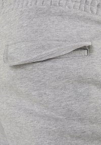 Grijze katoenen joggins met een zachte textuur, elastische tailleband en een zichtbare platte zak aan de zijkant.