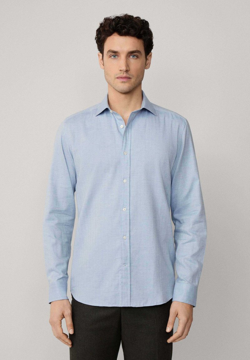 Camicia button-up azzurra chiaro realizzata in tessuto intrecciato, con maniche lunghe, colletto classico e una texture liscia. Motivo sottile visibile.