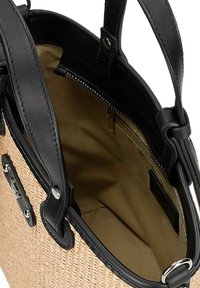 Le maniglie in pelle nera incorniciano una borsa intrecciata color sabbia. L'interno presenta una fodera beige liscia con una tasca con zip per lo stoccaggio.