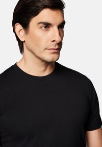 Czarny t-shirt z krótkim rękawem wykonany z gładkiego materiału, z klasycznym okrągłym dekoltem i dopasowanym krojem, prezentowany na jednolitym tle.