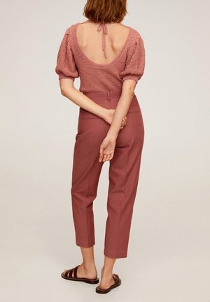 Top de punto con mangas abullonadas y escote en la espalda en rosa empolvado, combinado con pantalones rosados a medida y sandalias de slide marrones.