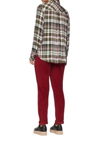 Gekeurde blouse met lange mouwen in groen, wit en bordeaux; gecombineerd met rode corduroy broek; zwarte sneakers met een gestructureerde zool.