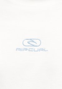 Λευκό ύφασμα με απλικέ σήμα Rip Curl σε ανοιχτό μπλε, με μια στιλιζαρισμένη κύμα μέσα σε οβάλ πάνω από το όνομα της μάρκας.