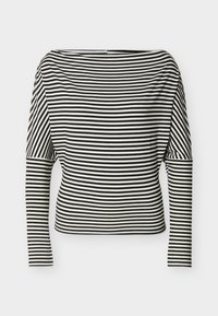 Ασπρόμαυρη ριγέ οριζόντια μπλούζα με μακριά μανίκια, με λαιμόκοψη τύπου βάρκα και εφαρμοστά μανίκια σε απλό φόντο.