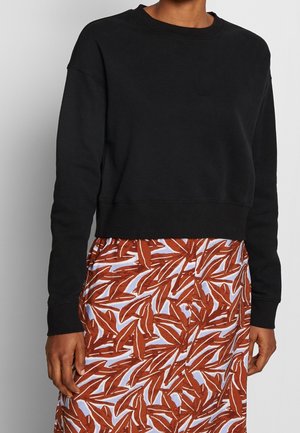 Svart kortad sweatshirt med långa ärmar, ribbad halsringning och manschetter. Kombinerad med en mönstrad kjol med röda och blåa bladdesigner.