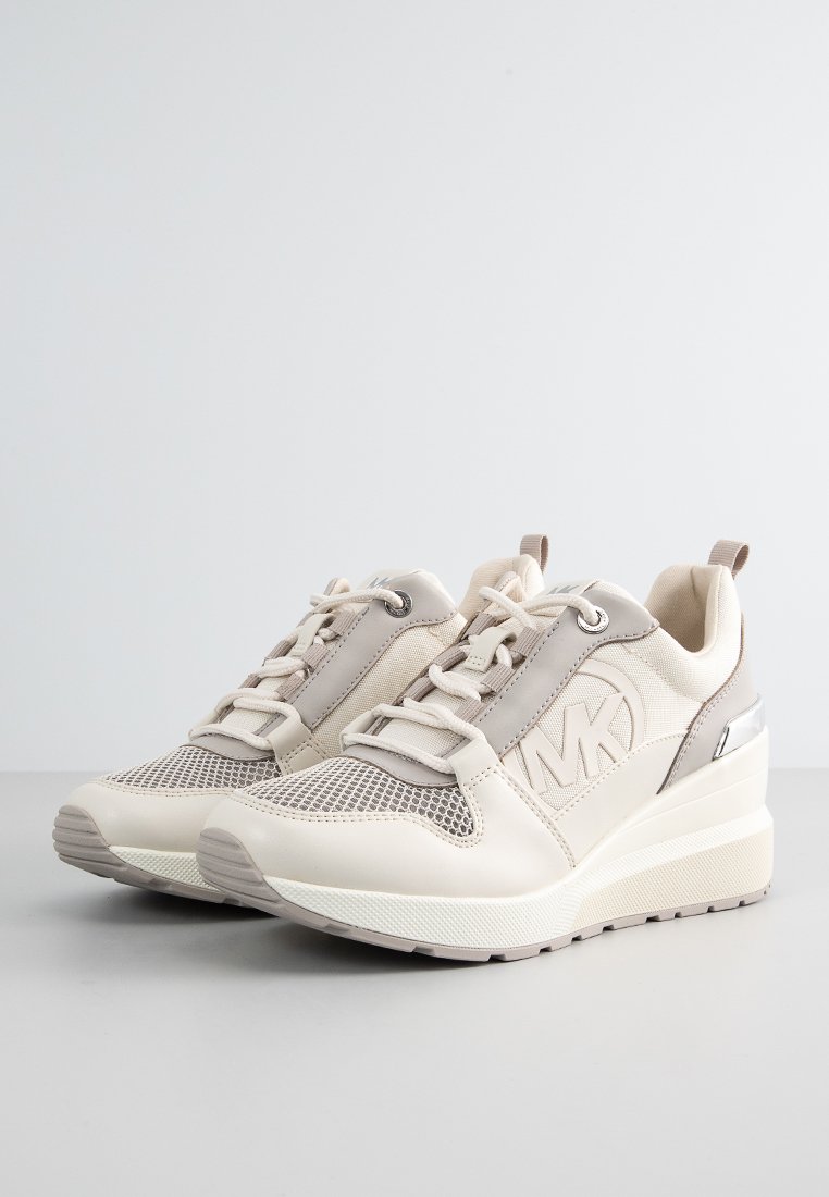 Sneakers beige con una combinazione di pelle liscia e mesh nella parte superiore. Suola intermedia ammortizzata e dettaglio metallico sul tallone. Design con chiusura a lacci.