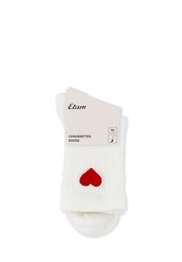 Białe skarpetki w prążki z małym czerwonym serduszkiem wyszytym w pobliżu kostki, zapakowane z beżową etykietą z napisem "Etam" i "Chaussettes Socks."
