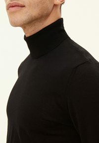 Maglione a collo alto nero realizzato in tessuto lavorato a maglia. Design aderente con dettaglio del collo a coste, texture liscia e senza motivi visibili.