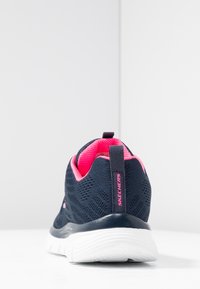 Tumši zili acu sieta sporta apavi ar rozā akcentiem, noapaļota forma un balta zole. Iespējas ietver pacelšanas cilpu un zīmola detaļu uz papēža.