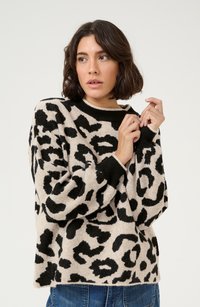 Maglione leopardato in morbido tessuto, con una base crema e macchie nere, maniche lunghe e un colletto e polsini a coste neri.