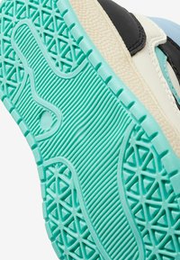 Sko s podešví s tyrkysovým texturovaným gripem, krémovým mezipodešví a viditelným černým a světle modrým vrchním materiálem.